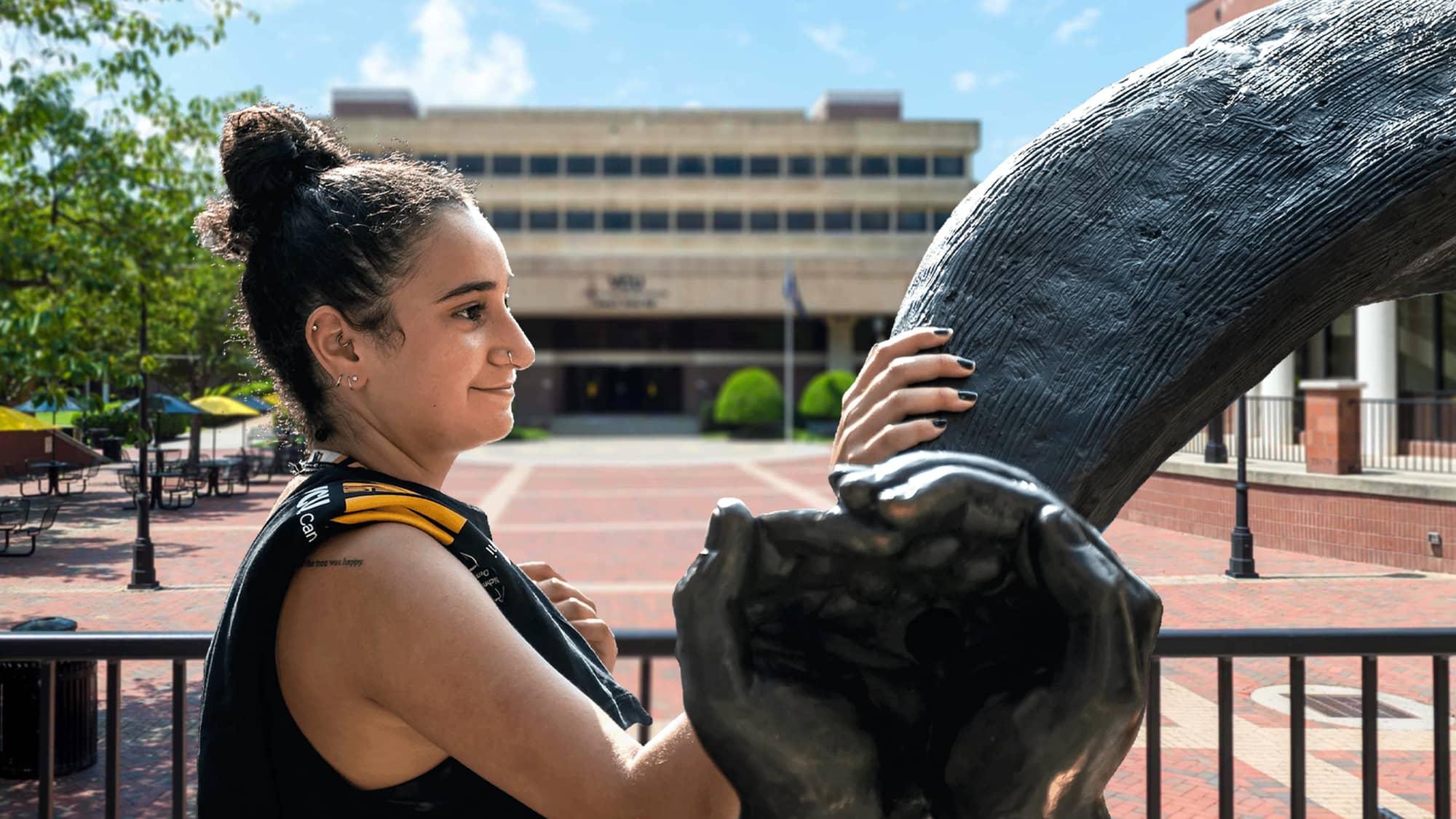 Female VCU student stading by the Rams Horns sculpture outside the The Commons.