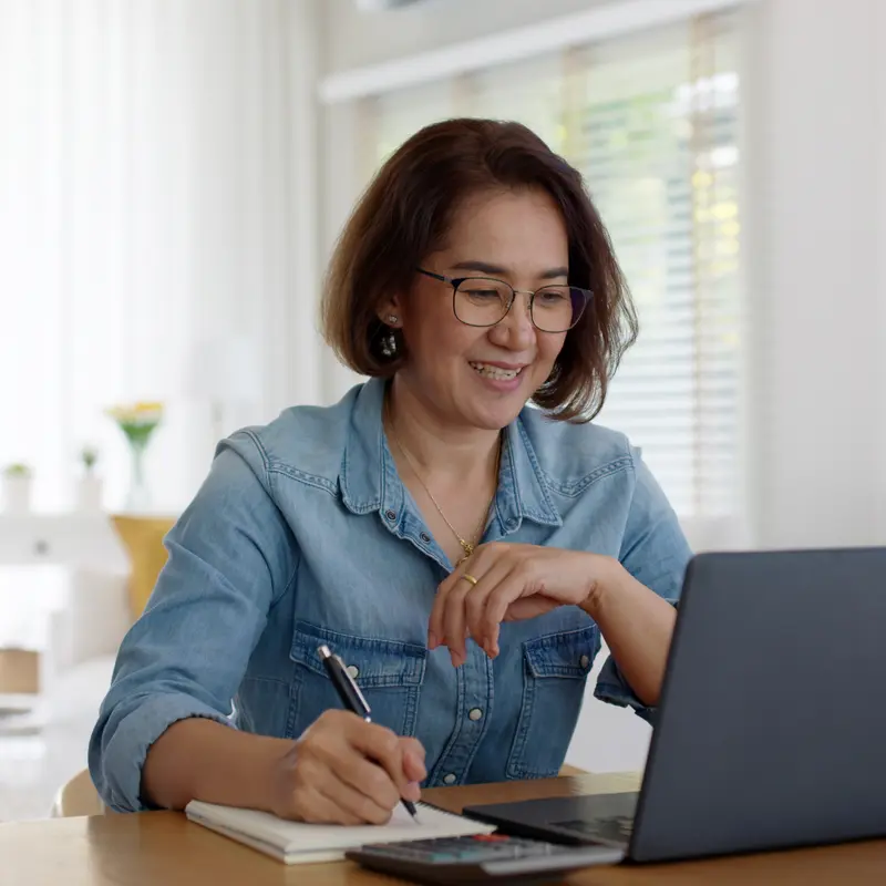 Adult learner taking notes while studying on a laptop, representing flexible learning in VCU’s online degree programs.
